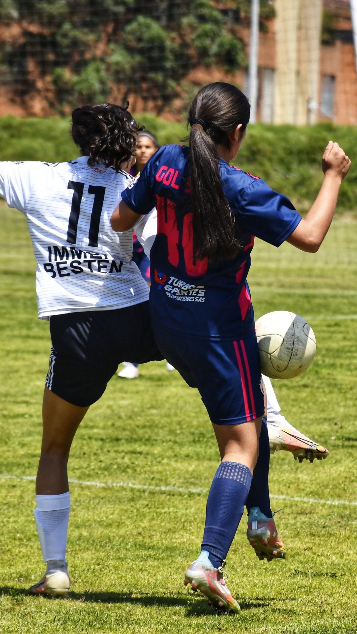 Dynamic soccer match with two women competing for the ball on a grassy field.